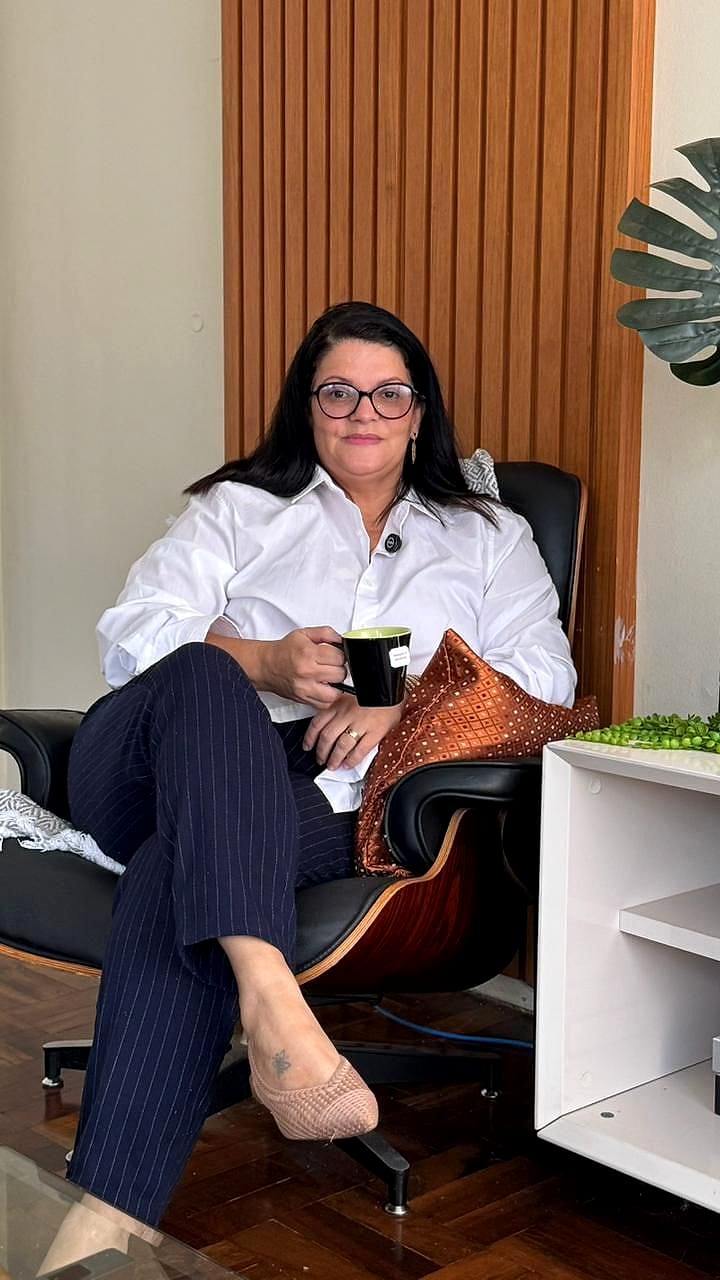 Sofia Nantes sentada na poltrona onde atende, com uma caneca na mão